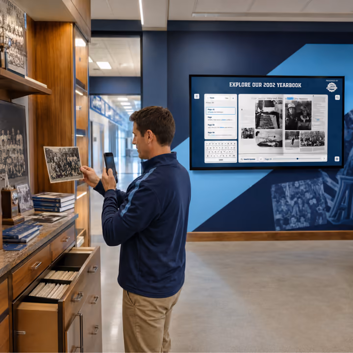 A staff member photographs old school photos with a phone