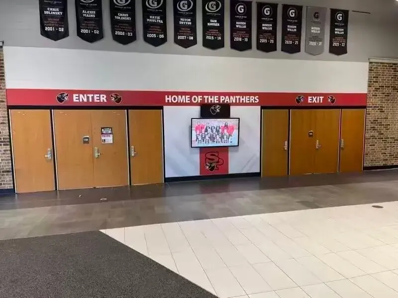 A wall-mounted Rocket touchscreen between two sets of gym doors